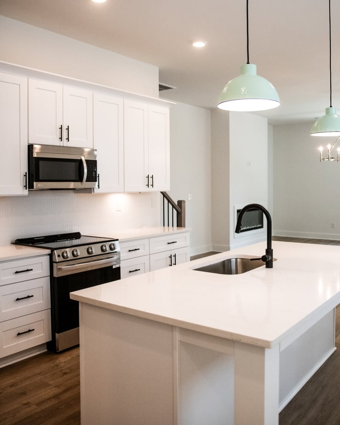 A custom home renovation of a kitchen with an island sink and white cabinets and brown wood flooring